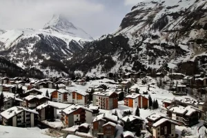 Winter view of Zermatt, Swiss ski resort surrounded by snow-capped mountains, picturesque village with alpine chalets, Matterhorn visible in the background, luxury destination in Switzerland, mountain getaway, private VTC transport from Geneva, premium transfer to ski resorts, winter stay in the Alps with private driver, car-free village.